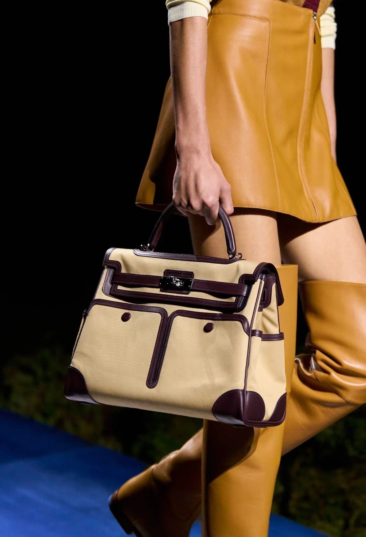 Cream and burgundy handbag carried with a golden outfit